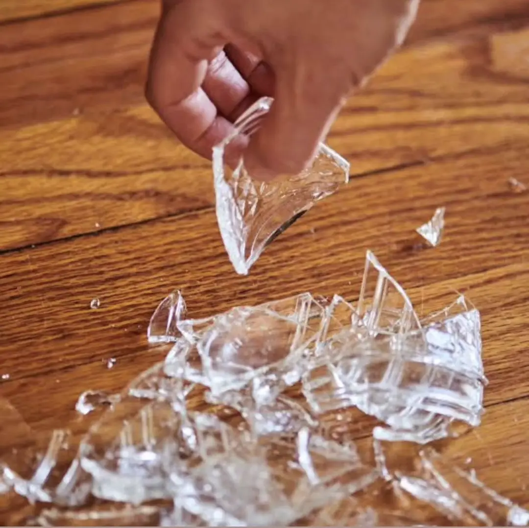 Stock image closeup of a smashed glass or bowl. A hand is picking up a broken piece.